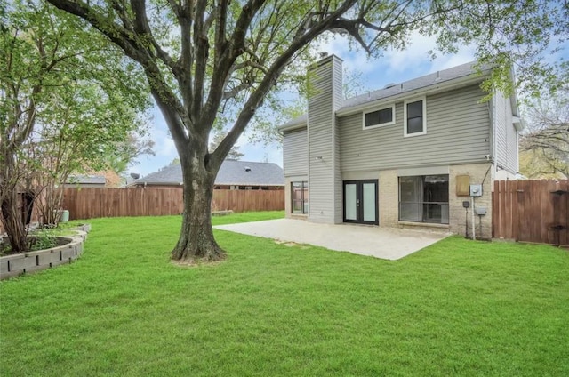 back of house with a lawn, a patio, a chimney, and a fenced backyard