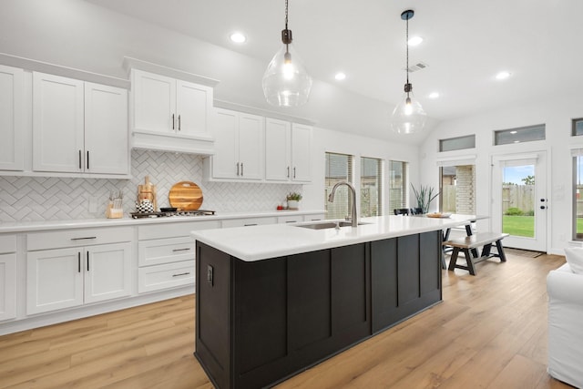 kitchen with light countertops, a sink, light wood-style floors, and tasteful backsplash