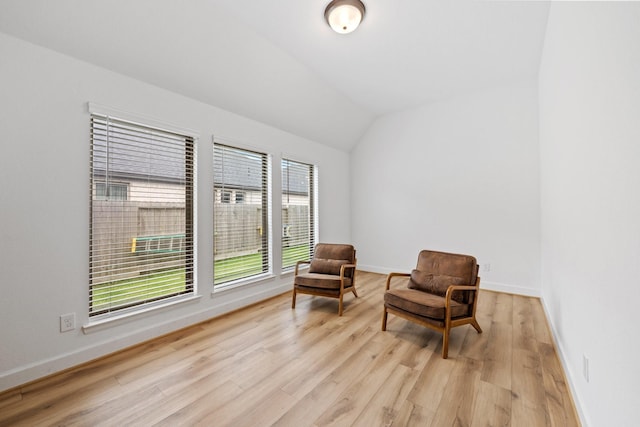 living area with baseboards, light wood-style flooring, and lofted ceiling