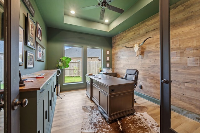 office area featuring ceiling fan, a raised ceiling, wooden walls, recessed lighting, and light wood-style flooring