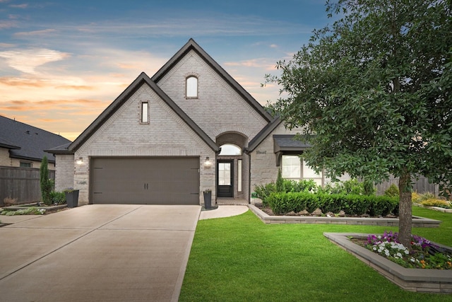 french country style house with brick siding, a yard, stone siding, and concrete driveway