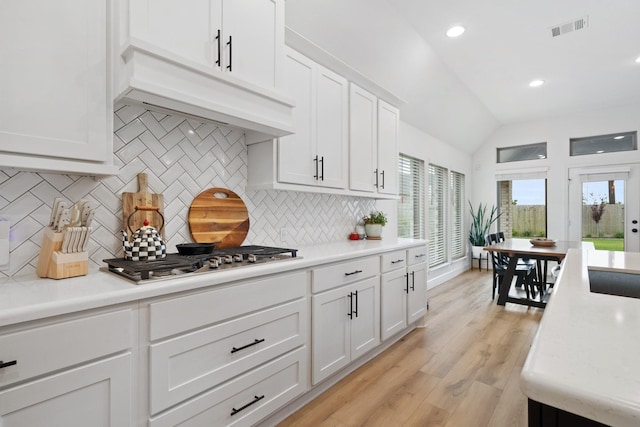 kitchen featuring light countertops, decorative backsplash, stainless steel gas cooktop, and visible vents