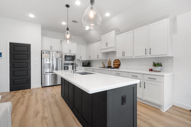 kitchen with light countertops, white cabinetry, a sink, appliances with stainless steel finishes, and backsplash