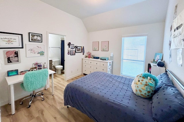 bedroom featuring baseboards, ensuite bathroom, vaulted ceiling, and light wood-style flooring