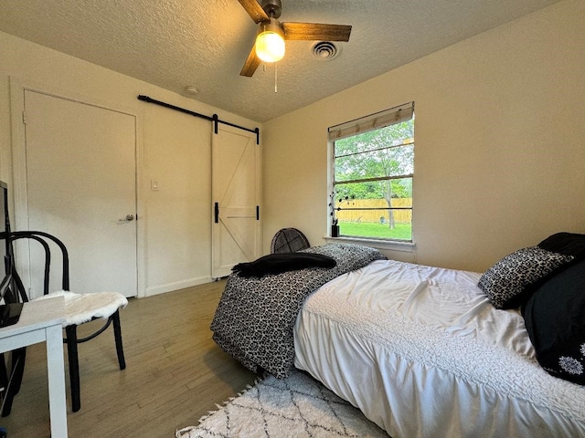 7006 Jalna St, Houston, TX 77055 - bedroom with a barn door, wood finished floors, a textured ceiling, and a ceiling fan