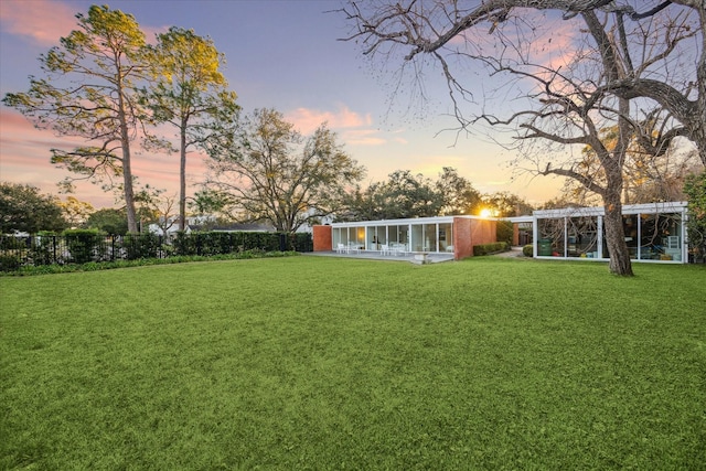 yard at dusk featuring fence private yard and a sunroom