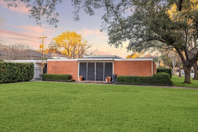 rear view of house featuring brick siding, a yard, and a sunroom