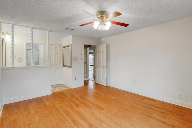 unfurnished room with visible vents, a ceiling fan, light wood-style flooring, and a textured ceiling