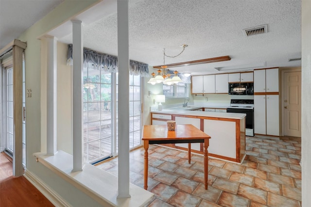 kitchen featuring range with electric stovetop, visible vents, black microwave, light countertops, and a peninsula