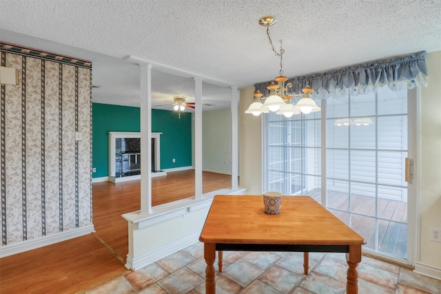 unfurnished dining area with baseboards, a textured ceiling, wood finished floors, and ceiling fan with notable chandelier