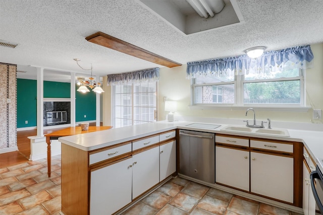 kitchen featuring stainless steel dishwasher, visible vents, a peninsula, a textured ceiling, and a sink