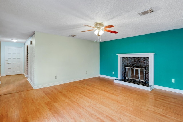 unfurnished living room featuring a ceiling fan, a textured ceiling, visible vents, and wood finished floors