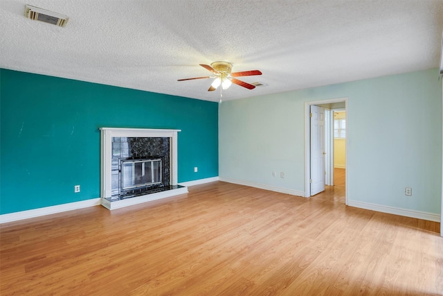 unfurnished living room featuring visible vents, light wood-style floors, baseboards, ceiling fan, and a textured ceiling