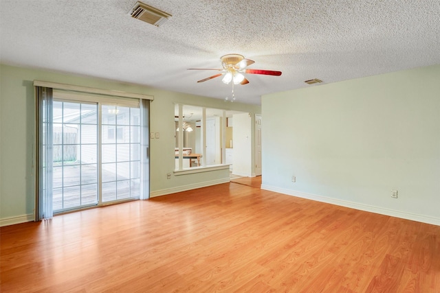 spare room with visible vents, light wood-style flooring, a textured ceiling, and ceiling fan with notable chandelier