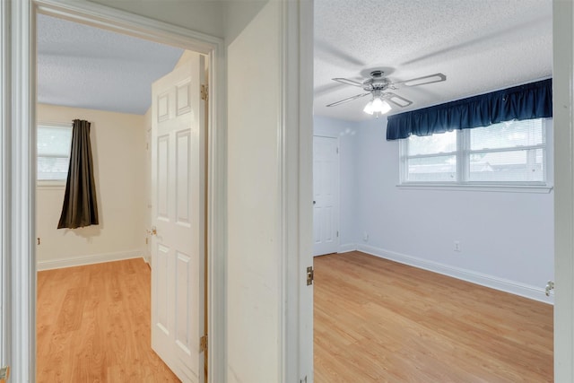 interior space with baseboards, light wood finished floors, and a textured ceiling