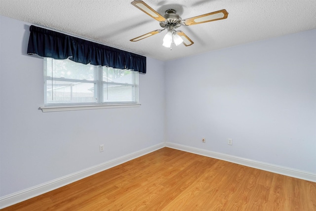 spare room featuring baseboards, ceiling fan, a textured ceiling, and light wood-style flooring