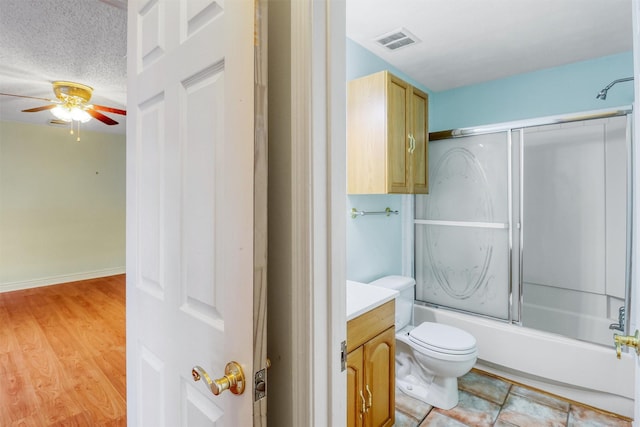 bathroom featuring vanity, toilet, a ceiling fan, visible vents, and bath / shower combo with glass door