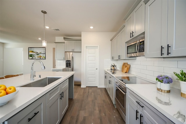 kitchen with backsplash, a sink, light countertops, gray cabinetry, and stainless steel appliances