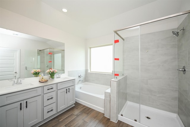full bathroom featuring double vanity, a shower stall, a sink, and a garden tub