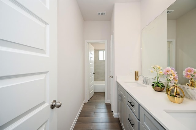 bathroom with double vanity, a bath, visible vents, a sink, and tile patterned floors