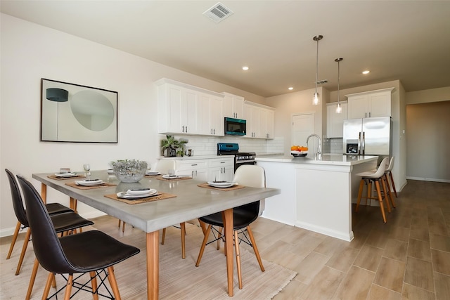 21807 Ash Cypress Ct, Cypress, TX 77433 - kitchen with appliances with stainless steel finishes, backsplash, a kitchen breakfast bar, a sink, and white cabinets