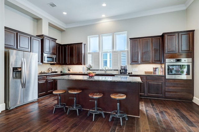 2125 Mcilhenny St, Houston, TX 77004 - kitchen with a kitchen breakfast bar, a kitchen island, a sink, dark stone counters, and stainless steel appliances