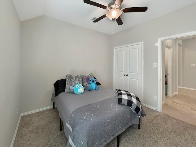 carpeted bedroom featuring ceiling fan, baseboards, vaulted ceiling, visible vents, and a closet