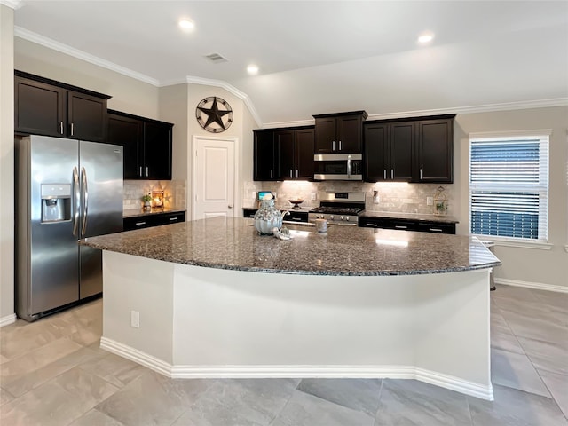 kitchen with appliances with stainless steel finishes, dark stone countertops, a large island with sink, tasteful backsplash, and visible vents