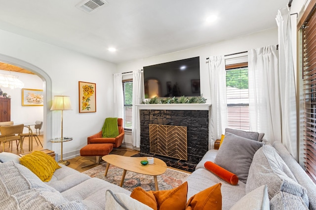 living room featuring a fireplace, arched walkways, recessed lighting, baseboards, and visible vents