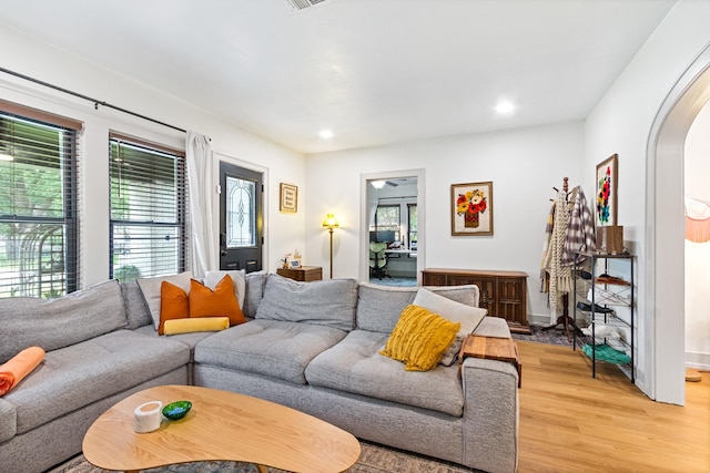 living area featuring light wood-style floors, arched walkways, and recessed lighting