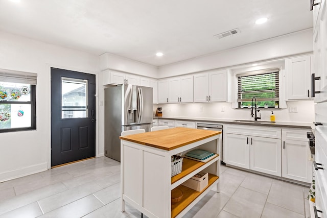 kitchen with visible vents, white cabinetry, a sink, wood counters, and appliances with stainless steel finishes