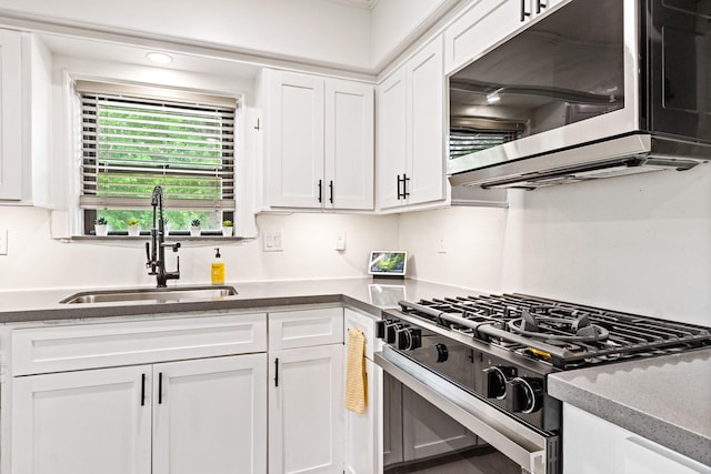 kitchen with white cabinetry, stainless steel microwave, range with gas stovetop, and a sink