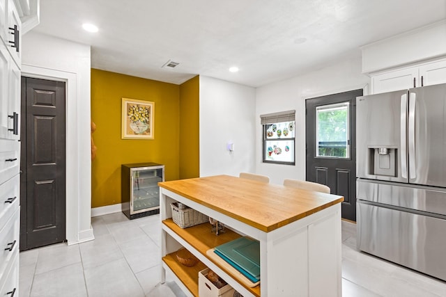 kitchen featuring visible vents, wooden counters, beverage cooler, stainless steel refrigerator with ice dispenser, and white cabinetry