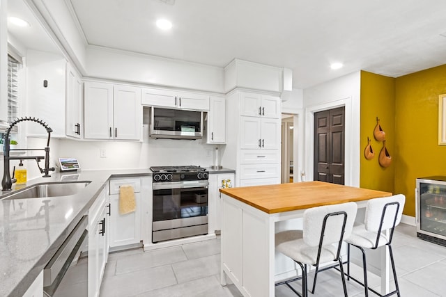 kitchen featuring wine cooler, light tile patterned floors, stainless steel appliances, and a sink