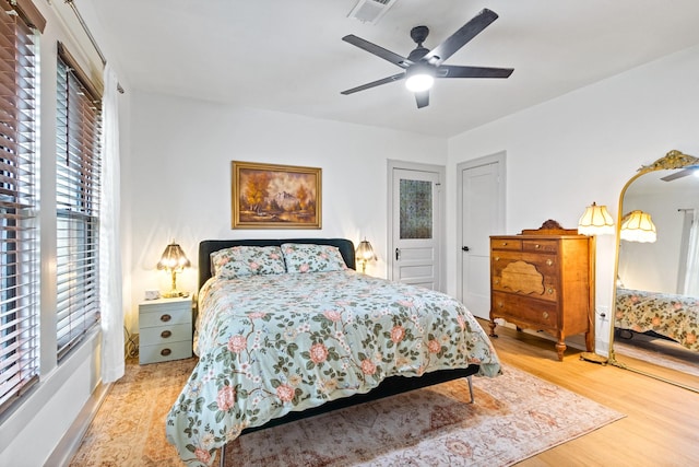 bedroom featuring visible vents, ceiling fan, wood finished floors, and multiple windows