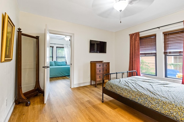 bedroom featuring a ceiling fan, baseboards, and light wood-style flooring