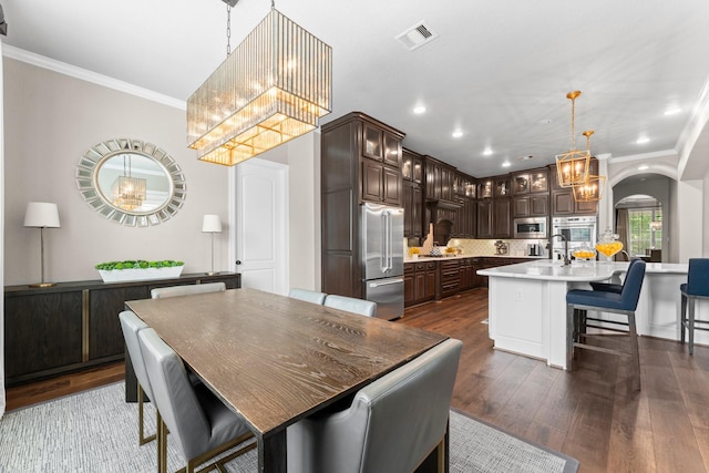 dining room featuring crown molding, arched walkways, visible vents, and a notable chandelier