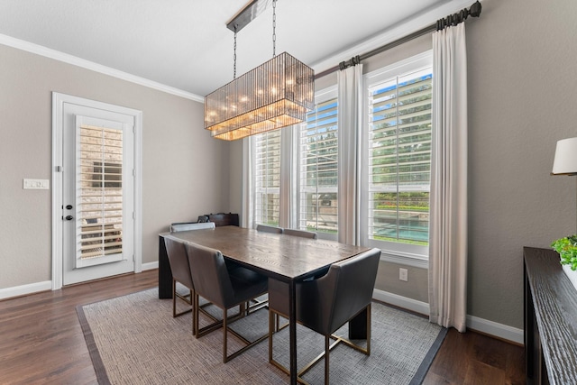 dining room featuring baseboards, ornamental molding, dark wood finished floors, and an inviting chandelier