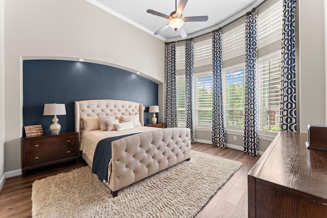bedroom featuring ornamental molding, wood finished floors, baseboards, ceiling fan, and arched walkways
