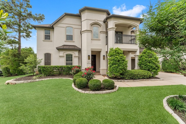 mediterranean / spanish home with stucco siding, a front lawn, and a balcony