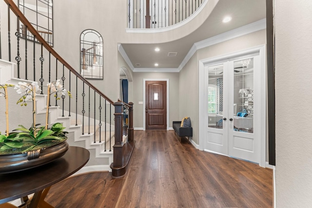 entryway featuring french doors, a towering ceiling, wood finished floors, stairway, and ornamental molding