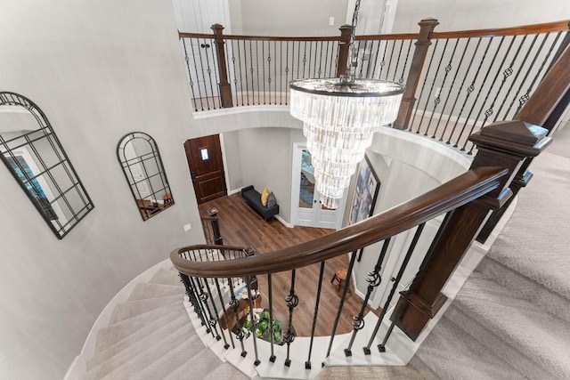 stairs featuring a towering ceiling, baseboards, carpet flooring, and a notable chandelier