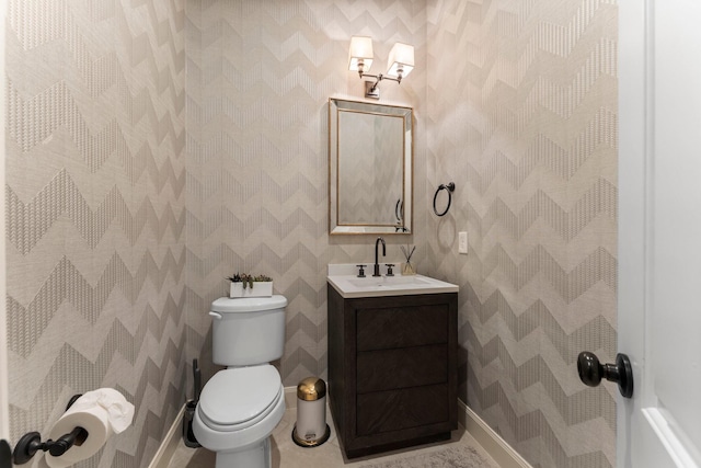 half bath featuring baseboards, tile patterned floors, toilet, and vanity