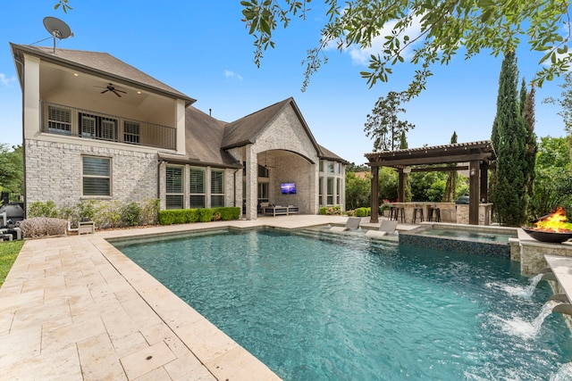 view of pool featuring a pool with connected hot tub, exterior kitchen, an outdoor bar, a patio area, and a ceiling fan