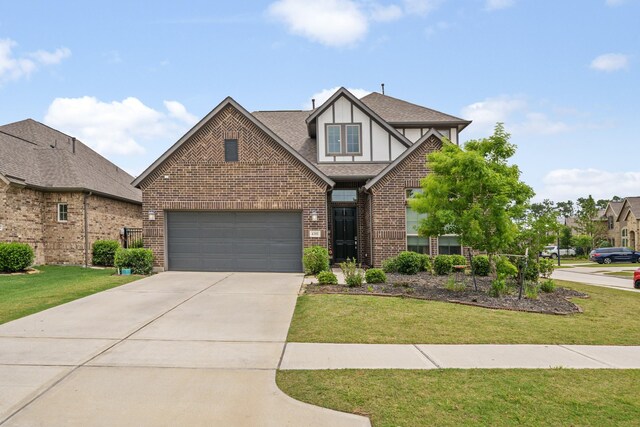 4381 Victoria Pine Dr, Spring, TX 77386 - tudor home featuring concrete driveway, brick siding, a front yard, a garage, and roof with shingles