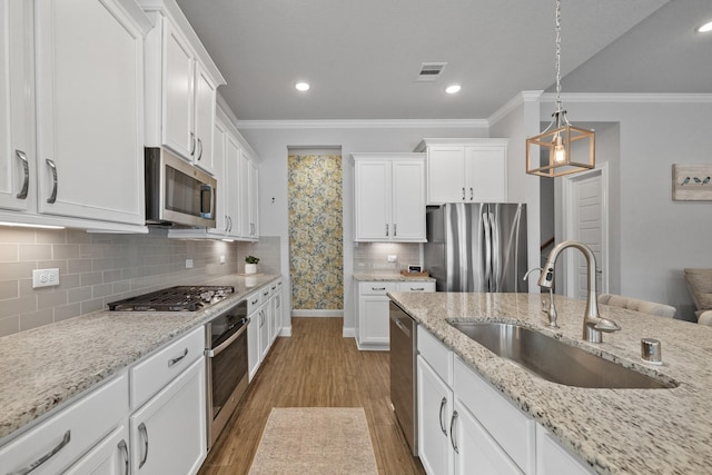 4381 Victoria Pine Dr, Spring, TX 77386 - kitchen with appliances with stainless steel finishes, a sink, crown molding, white cabinets, and light wood-style floors