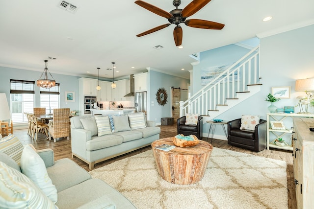 living area featuring crown molding, visible vents, wood finished floors, and stairway