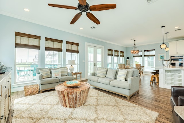 living area featuring visible vents, crown molding, wood finished floors, and french doors