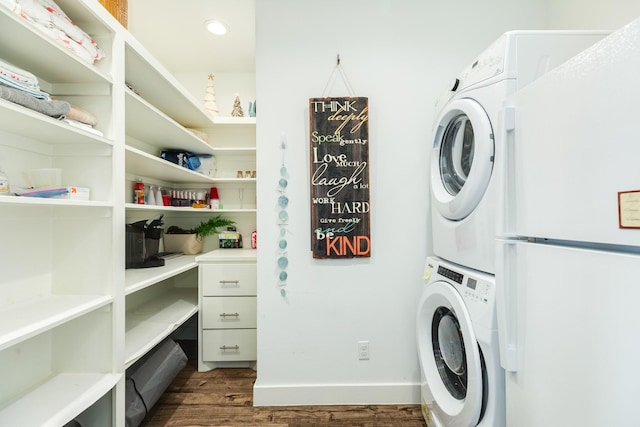 clothes washing area featuring laundry area, dark wood-style flooring, stacked washing maching and dryer, baseboards, and recessed lighting