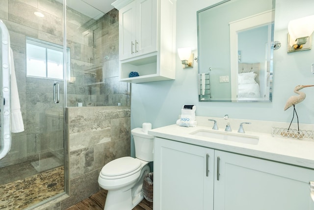 full bath featuring toilet, a shower stall, wood finished floors, and vanity